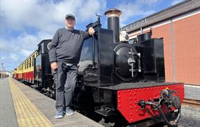 Pete Waterman standing in front of a Vale of Rheidol steam engine